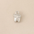 Vista macro di un ciondolo a forma di dente in argento lucido con viso sorridente e capelli d'oro - Stile Dente Antropomorfo Argentato / Argento