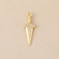 Macro shot of gold sword pendant with zircon stones on a soft pink textured fabric - Gold