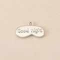 Macro detail of 18K gold-plated copper Good Night eye mask pendant with frosted metal texture - Good Night Letter Sleep Mask Style / Silver