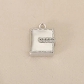 Macro detail of silver book pendant with micro-inlaid zircons on beige fabric - Silver