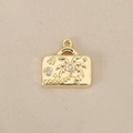 Macro detail of suitcase-shaped gold pendant with palm tree relief and zircon - Gold