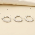 Macro-opname van drie zilveren oorringen met zirkonia en kleine ophanglussen voor DIY-sieraden - Zilver