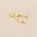Macro view of polished 18K gold plated copper wishbone pendant on beige linen - Gold