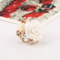 Detailed shot of white resin roses and clear faceted stones on a floral gold ring - White