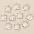 Macro shot of ten square silver-plated pendants with cubic zirconia on beige fabric - Silver Square Style (Style 1)