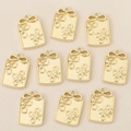 Detailed view of ten gold-plated floral butterfly pendants on a soft beige fabric - Gold Style 1