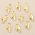 Macro detail of ten gold leaf charms for DIY jewelry making on a textured background - Gold Leaf Shape