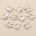 Macro view of ten small silver bee pendants with zircon inlay on textured fabric - Silver Bee Style
