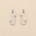 Macro detail of silver U-shaped twisted chain link pendants with sparkling zircon inlays - Left / Silver