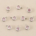 Dettaglio ravvicinato di 10 ciondoli tondi in argento con pietre rosa sfaccettate - Argento Rosa