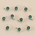 Vista macro di ciondoli rotondi placcati oro 18k con zircone verde per gioielli fai-da-te - Argento/Verde