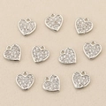 Macro detail of ten heart pendants with white zircons on a textured beige fabric background - Silver Pave Zirconia Heart (Style 11)