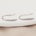 Detailed view of silver-plated earring hooks with cubic zirconia on champagne silk fabric - Silver