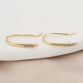 Macro shot of 18K gold-plated U-shaped ear hooks with inlaid stones on silk background - Gold