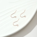 Tres ganchos para pendientes chapados en oro rosa sobre un plato de cerámica para joyería DIY - Rosa oro