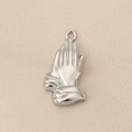 Detailed macro view of polished silver praying hands pendant with hammered texture details - Silver