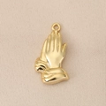 Detailed view of prayer hands gold pendant with hammered texture on beige fabric - Gold