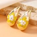 Makro-Detail von C-förmigen Tropfenohrringen mit gelbem Emaille-Blumenmuster auf Goldmetall - Wassertropfen Blumenstil / Umweltfreundliches Gelb helles KC Gold