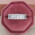 Macro shot of emerald cut zircon eternity band in a pink velvet octagon jewelry box - US 5 / White