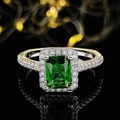 Macro view of a rectangular green emerald ring with sparkling pavé diamonds on black mirror - US 5 / Green