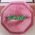 Close-up of luxury silver band ring with green emerald-cut stones in a pink velvet box - US 5 / Green