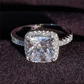 Macro shot of cushion cut halo engagement ring with pavé diamond band on purple velvet - Size 5 / White