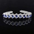 Silver bangle with rectangular blue gems and pavé zircon crystals on a black mirror surface - Blue Geometric Style