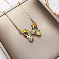 Macro shot of colorful gradient crystal butterfly pendant with rose gold box chain details - Yellow