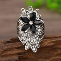 Anillo de flor retro plateado con piedras negras y cristales blancos sobre madera - Negro Plata Antigua
