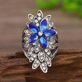 Vintage Silberring mit blauen Edelsteinen und Kristallen auf rustikalem Holzhintergrund - Antiksilber Königsblau