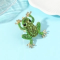 Macro-detail van een gouden kikkerring met groene strass-steentjes op een schelpplaat - Groen Simulatie Goud (X2469)