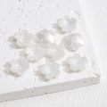 Makro-Detail von neun perlweißen Harzblumenperlen für die DIY-Schmuckherstellung - Weiß