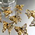 Macro detail of golden butterfly charm with black gem and ink calligraphy art - Gold