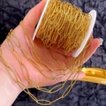 Golden textured oval link chain for DIY jewelry making on white spool with hand detail - Gold-6x21
