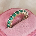 Exquisite gold ring featuring a row of vibrant green round-cut gemstones in a pink velvet box - Gold Green