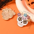 Detail view of sugar skull earrings with floral enamel patterns and 3.5cm dimension markings - Light KC Gold