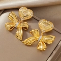 Dettaglio di orecchini a fiocco dorati con ciondoli a cuore e strass luccicanti - Stile Cuore a Fiocco Oro (WEH4966)