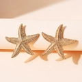 Golden starfish stud earrings with a textured beaded finish on a white display pedestal - Textured Starfish Style (WEH6048) / Gold Plated