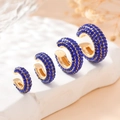 Détail de quatre bagues d'oreille dorées en forme de C serties de zircons bleus - Or Bleu Roi