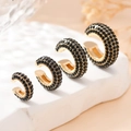Gros plan de quatre boucles d'oreilles C dorées serties de cristaux de zircon noirs - Noir Or