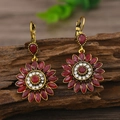 Dettaglio di orecchini vintage a girasole con strass rossi su legno scuro - Rosso Oro KC Antico (EH4540)