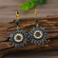 Dettaglio macro di orecchini a girasole in oro antico con pietre blu su legno rustico - Blu Scuro Oro KC Antico (EH4540)