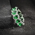 Macro view of emerald green oval-cut stones in a silver pave-set eternity ring - US 5 / Green