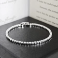 Close-up of sparkling white zircon tennis bracelet with fold-over clasp on a black box - 4mm-18cm / White