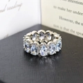 Silver eternity ring with oval-cut zircons and halo diamond setting on jewelry box - US 5 / White