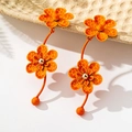 Detailed macro of bright orange floral drop earrings with a textured lacquer finish - Orange Dotted-Texture Long Flower Drop Earrings (en-19-e027-Orange)