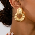 Nahaufnahme der goldenen Vintage-Ohrringe mit geometrischer Muschelform und Relief - Retro Relief Reifenstil