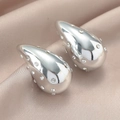 Primer plano de pendientes de gota plateados pulidos con cristales sobre seda color champán - Gota Plateada con Strass Blancos (WEH4898)