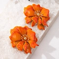 Detailed view of orange gradient enamel flower earrings with golden bead centers on stone - Orange