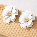 Detail showing elegant white floral earrings with layered petals and golden pistils - White